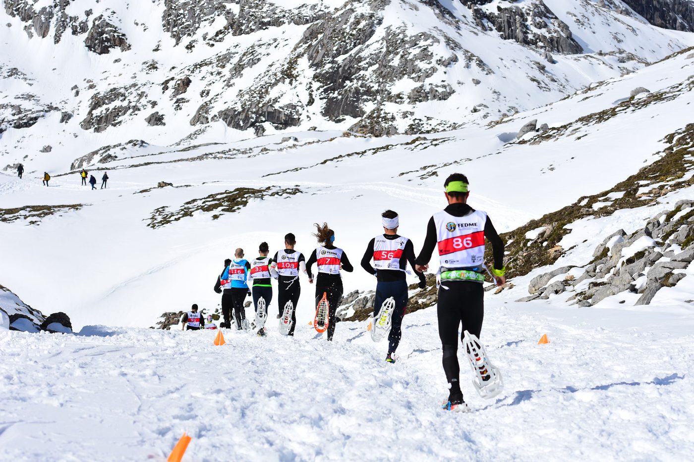 Grupo de corredores con raquetas de nieve subiendo la pendiente